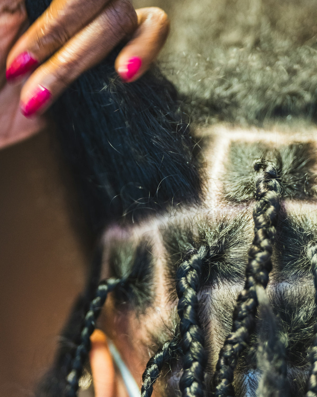 Hands braiding dark hair into square sections.